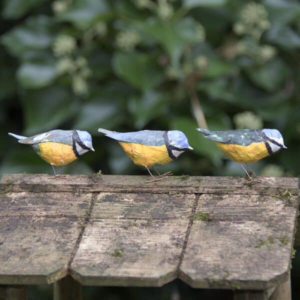 3 tiny papier mâché blue tits on the roof of a bird house