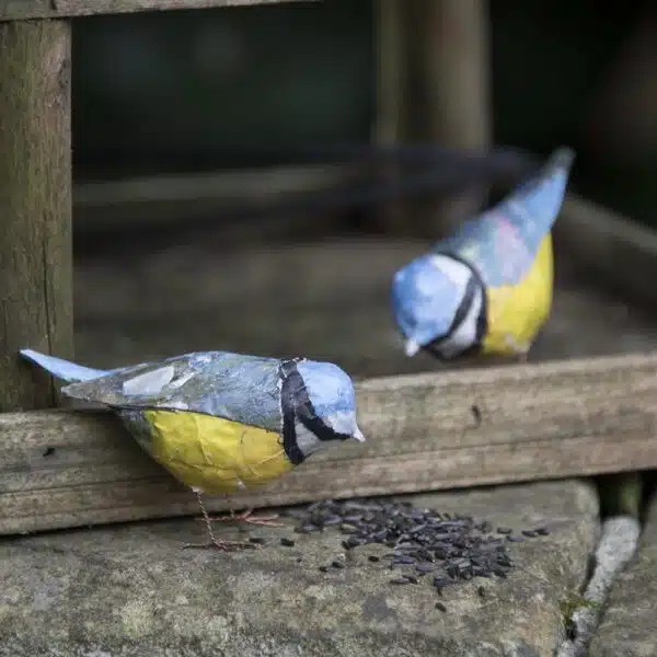 2 tiny papier mache blue tits in front of a bird house