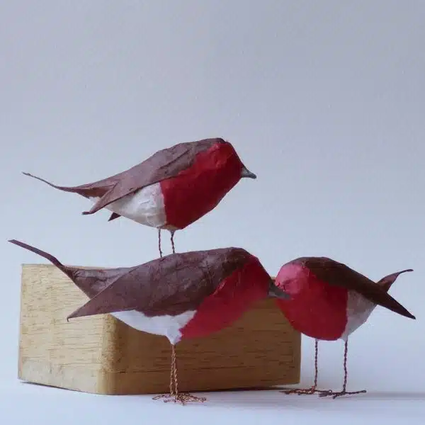 3 tiny papier mâché robins, perched on cotton reels