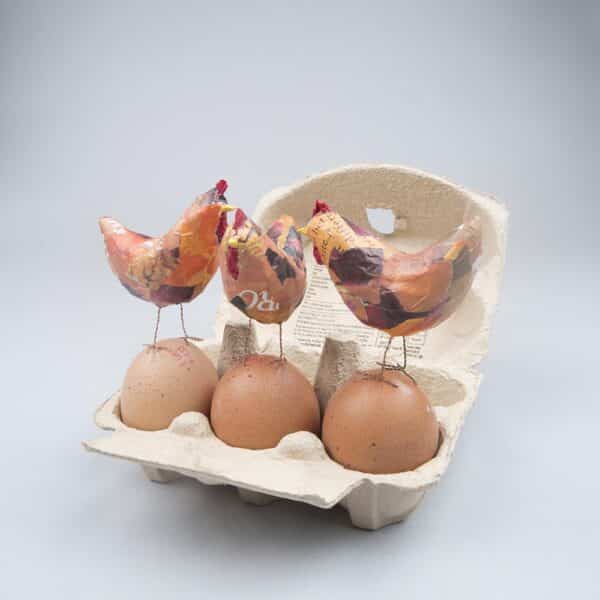 3 tiny chickens perched on an egg box