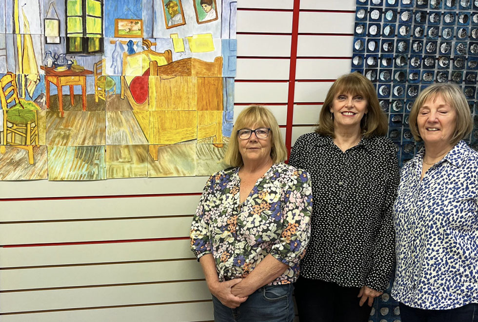 finished_project_jun26 copy 3 women standing next to a pastel artwork